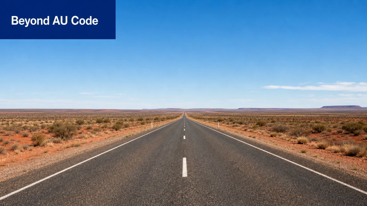 A long, straight asphalt road stretching through the vast, empty landscape of the Australian outback under blue sky.